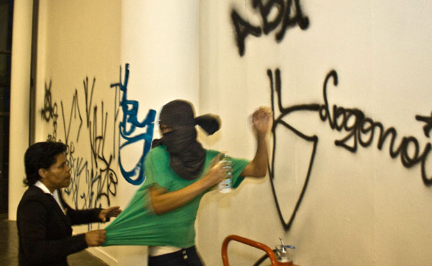 Funcionária da Bienal tenta deter pichador em ataque ao evento, em 2008. Episódio terminou em convite oficial.