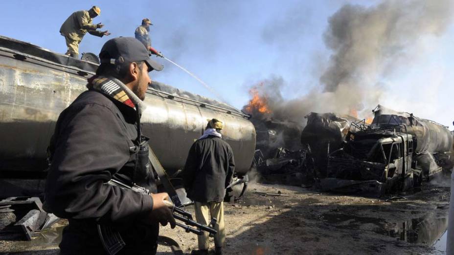 Policiais e bombeiros ao lado de caminhões de petróleo da Otan incendiados em ataque noturno de militantes em Quetta, Paquistão