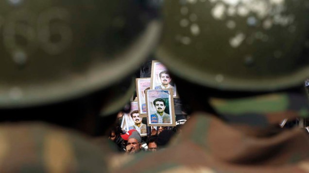 Policiais olham para membros da Frente de Libertação da Caxemira em Srinagar, Índia
