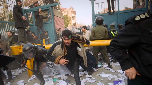 Policiais tentam capturar manifestantes que passam pelo portão da embaixada britânica no Teerã, Irã