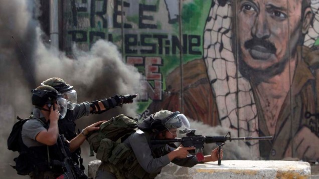 Policiais israelenses durante conflito com manifestantes no território palestino de Qalandiya