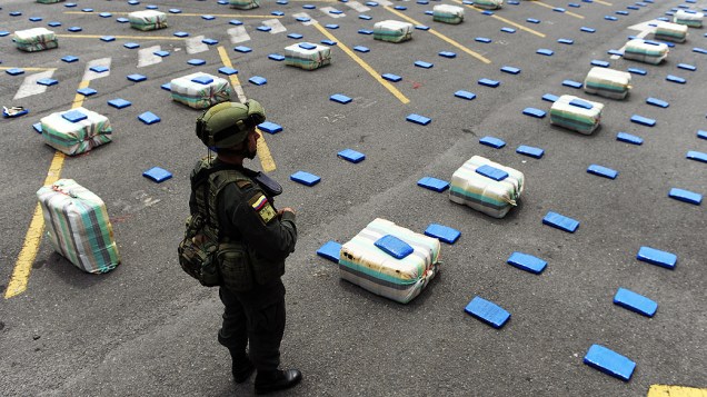 Policial colombiano anti-drogas monta guarda ao lado de pacotes de maconha, em Cali, no departamento de Valle del Cauca, na Colômbia. Anti-narcóticos da Polícia Nacional apreendeu duas toneladas de maconha durante a operação