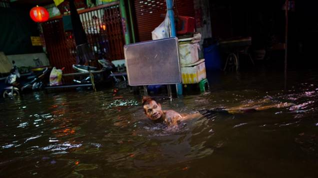 Tailandês nada em rua alagada em Bangcoc, Tailândia