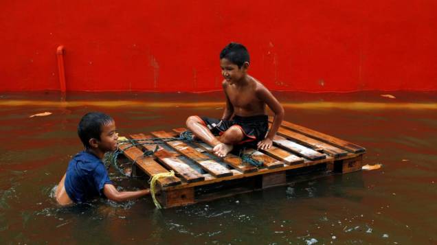 Garotos brincam em área alagada em Bangcoc, Tailândia
