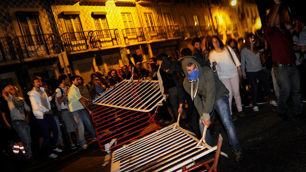 Manifestantes derrubam barricada que protegia o parlamento em Lisboa, durante protesto contra a previsão do orçamento de 2013 em Portugal