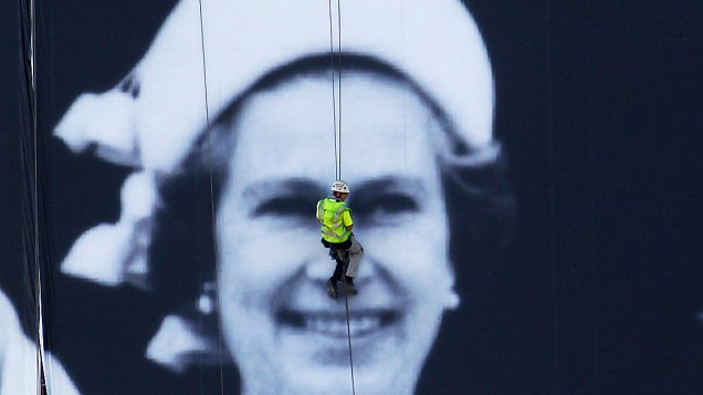 Homem trabalha na instalação de um enorme painel à beira do Rio Tâmisa, em Londres. O pôster gigante de 100 m por 70 m celebra agora o Jubileu de Diamante
