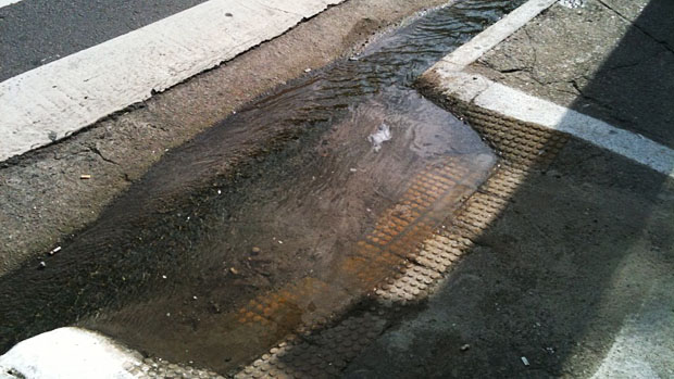 Água acumulada entre a rua e a rampa de acessibilidade. Mais uma dificuldade enfrentada por cadeirantes