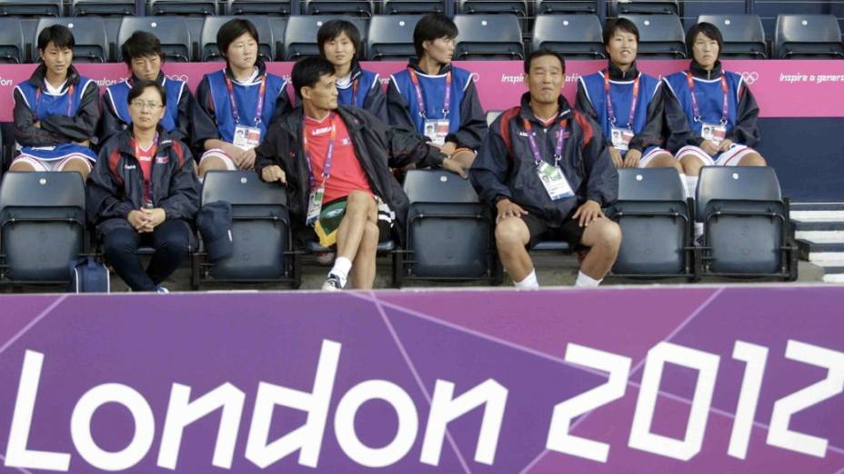 Jogadoras da seleção norte-coreana aguardam a resolução da crise provocada pela exposição da bandeira errada no jogo desta quarta, em Glasgow