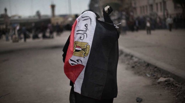 Mulher egípcia cobre-se com a bandeira do país que leva a frase "Não a Mubarak", na praça de Tahrir, no Cairo