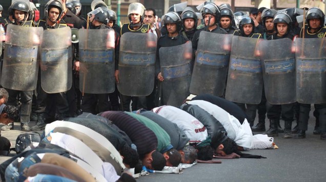 Vigiados por policiais, manifestantes rezam em frente a mesquita l-Istiqam no Cairo, Egito
