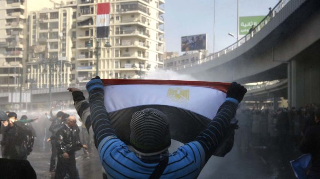 Durante protesto no Cairo, manifestante egípcio confronta a polícia com a bandeira nacional na mão - 28/01/2011