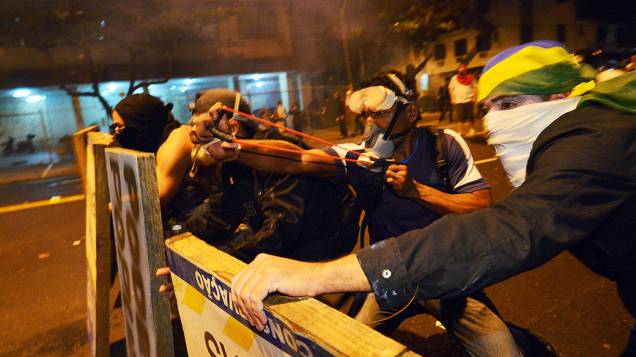 Manifestantes atirando pedras contra policia durante protesto em uma rua perto do estádio do Maracanã do Rio de Janeiro