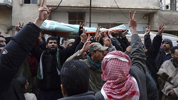 Manifestantes sírios carregam corpo de homem morto durante protesto em Homs