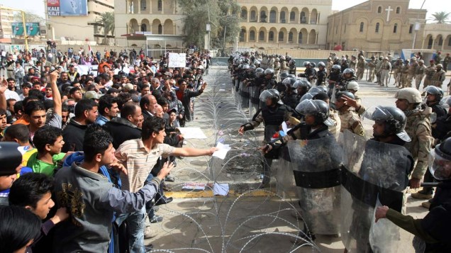 Manifestantes e policiais durante protesto contra a corrupção, o desemprego e a má qualidade dos serviços públicos na capital Bagdá, Iraque