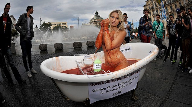 Garota da Playboy posa seminua dentro de banheira com sangue falso durante protesto da organização que defende os direitos dos animais PETA, em Munique, na Alemanha