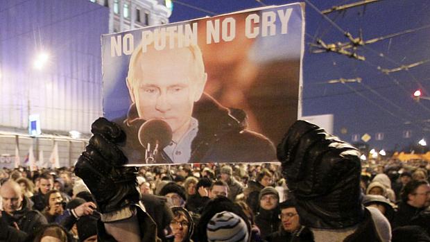 Manifestante mostra cartaz em que se lê "Não, Putin, não chore", em referência à música "No woman no cry", de Bob Marley