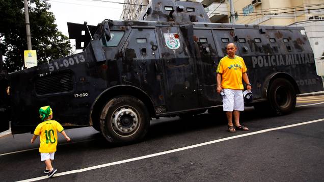 Torcedores brasileiros ao lado de um carro  Blindado da polícia fora do estádio do Maracanã antes da final da Copa das Confederações entre Brasil e Espanha, no Rio de Janeiro