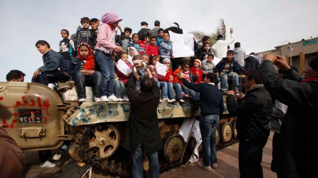Manifestantes colocam crianças em tanque de guerra durante os protestos contra o governo na cidade de Benghazi, Líbia