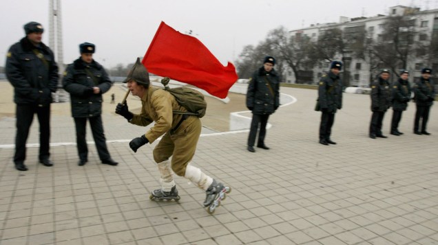 Homem do Partido Comunista passa em frente a policiais, durante protestos contra o resultado das eleições parlamentares, em Rostov-on-Don, Rússia - 10/12/2011