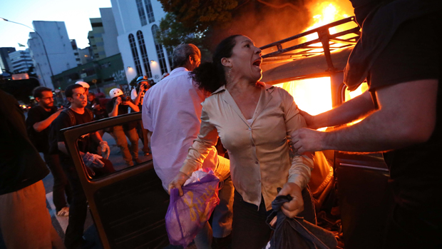 Mulher deixa o seu carro depois de manifestantes terem ateado fogo no veículo durante  protesto contra a realização da Copa do Mundo