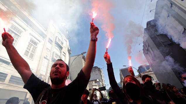 Rio de Janeiro - Manifestantes acendem sinalizadores e cobrem o rosto durante um protesto no centro do Rio
