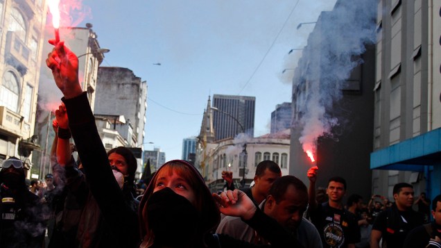 Rio de Janeiro - Manifestantes acendem sinalizadores e cobrem o rosto durante um protesto no centro do Rio