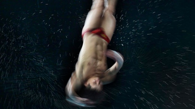 O chinês Qiu Bo realiza aquecimento antes da prova de saltos ornamentais nos Jogos Olímpicos da Juventude, em Cingapura