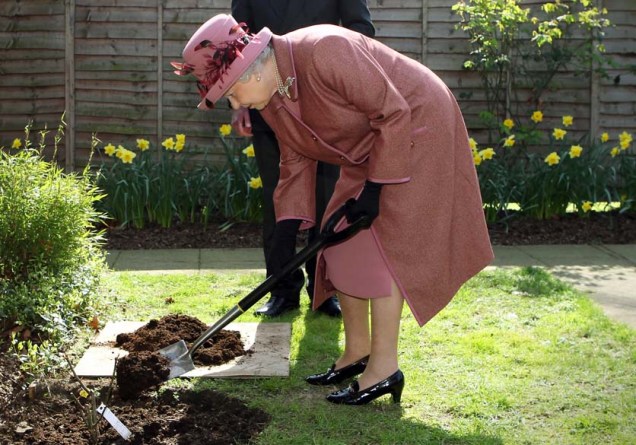Em Londres, a rainha Elizabeth II planta uma rosa durante visita na Fundação Real de Santa Katharine, a mais antiga instituição religiosa da Grã-Bretanha