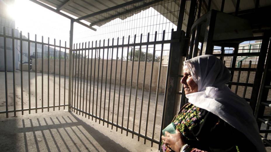 Mulher palestina cruza o ponto de controle de entrada para Jerusalém, onde irá participar das orações da primeira sexta-feira do Ramadã