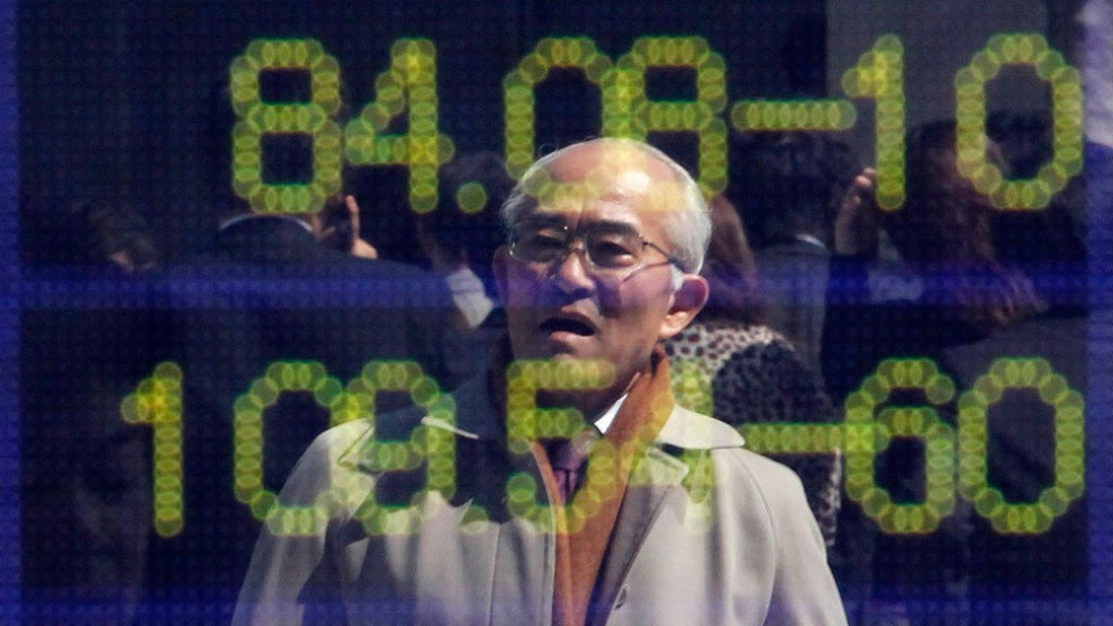 Reflexo de homem em painel eletrônico com índices da bolsa em Tóquio, Japão