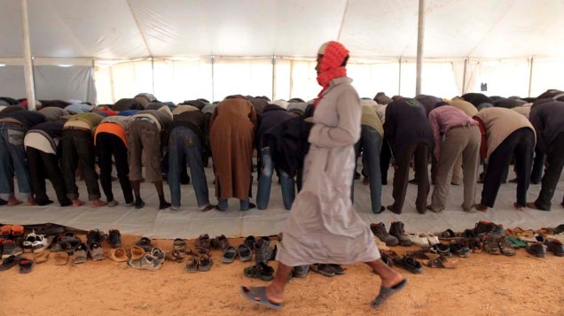 Imigrantes fugidos da Líbia rezam em mesquita improvisada na fronteira com a Tunísia, na cidade de Ras Jedir<br>	 