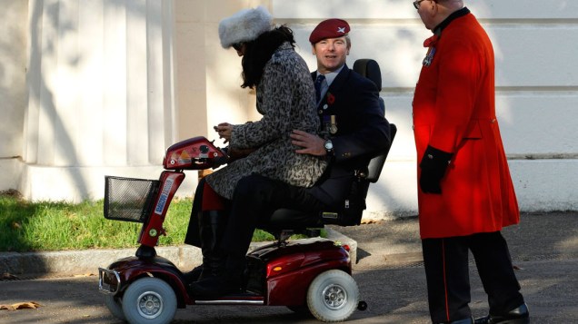 Veterano ferido em guerra leva a esposa em cadeira motorizada, durante a cerimônia do "Remembrance Day", em Londres