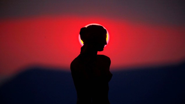 Por-do-sol visto atrás de réplica de estátua da Deusa Afrodite de Milo na ilha de Santorini, Grécia
