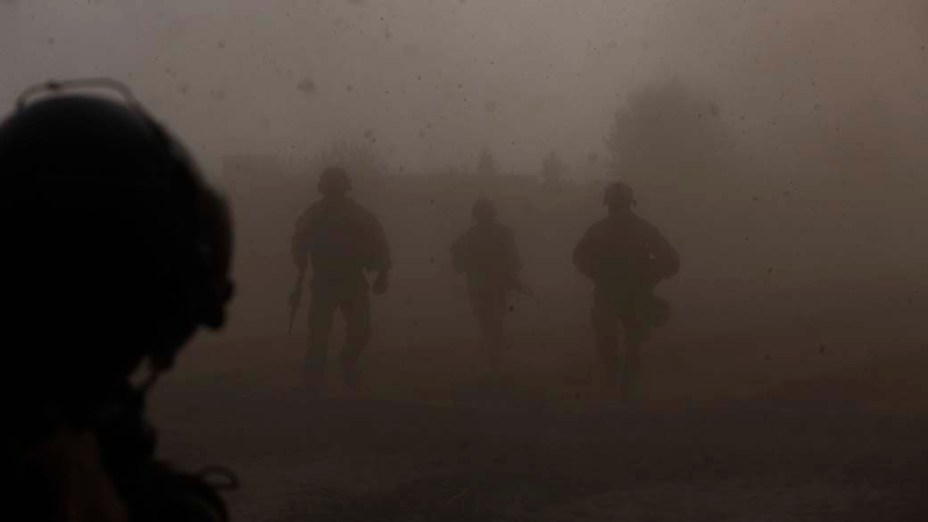 Em meio a uma densa camada de poeira, militares americanos ajudam a socorrer um fuzileiro naval ferido por explosivo no sul do Afeganistão
