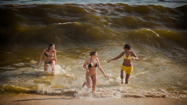 As pessoas tentam aliviar o forte calor com poucoas roupas, bastante líquido e mergulhos na praia, no Rio de Janeiro