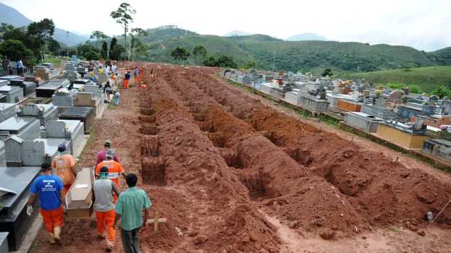 Trabalhadores carregam caixão entre as covas abertas em Teresópolis, Rio de Janeiro - 15/01/2011