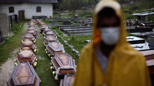 Debaixo de chuva, trabalhadores da prefeitura usam máscara para evitar infecções ao trabalhar no enterro das vítimas do deslizamento em Nova Friburgo, Rio de Janeiro - 15/01/2011