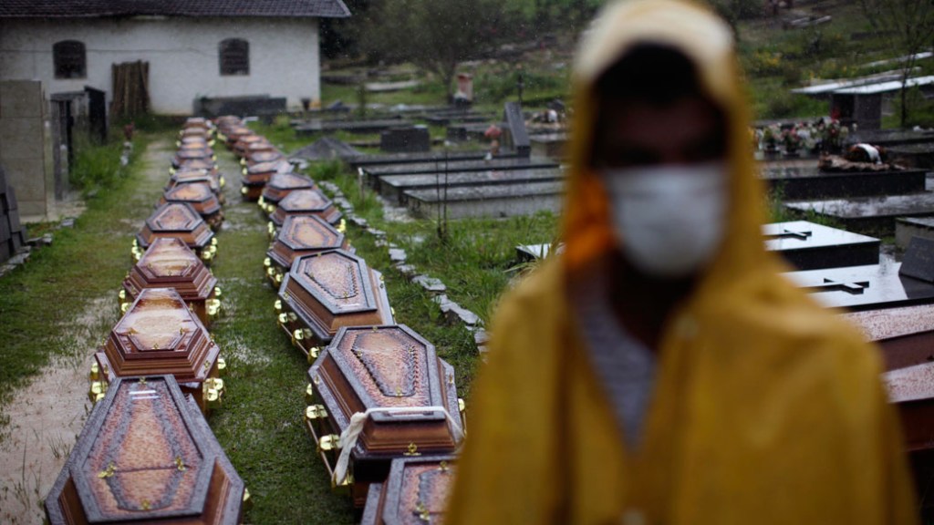 Debaixo de chuva, trabalhadores da prefeitura usam máscara para evitar infecções ao trabalhar no enterro das vítimas do deslizamento em Nova Friburgo, Rio de Janeiro - 15/01/2011