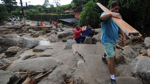 Moradores do bairro de Campo Grande carregam itens recuperados de suas casas após o deslizamento de terra em Teresópolis, Rio de Janeiro - 16/01/2011
