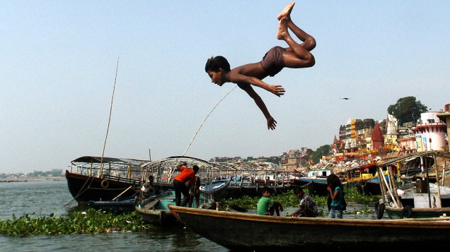 Criança mergulha no rio Ganges em Varanasi, também conhecida como a cidade mais sagrada do hinduísmo