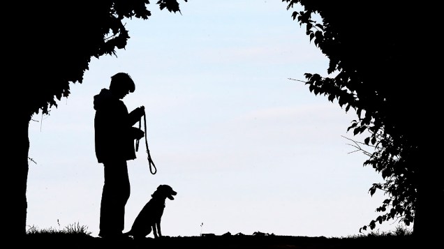 Homem passeia com seu cachorro à beira do rio Reno em Duisburgo, na Alemanha