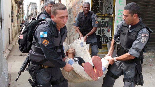 Policiais carregam suspeito morto durante troca de tiros na comunidade Mandela 2, no Rio de Janeiro