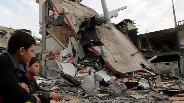 Garotos sentados próximos às ruínas da casa de um dirigente da Jihad Islâmica atingida por ataque aéreo israelense em Jabalia, na Faixa de Gaza