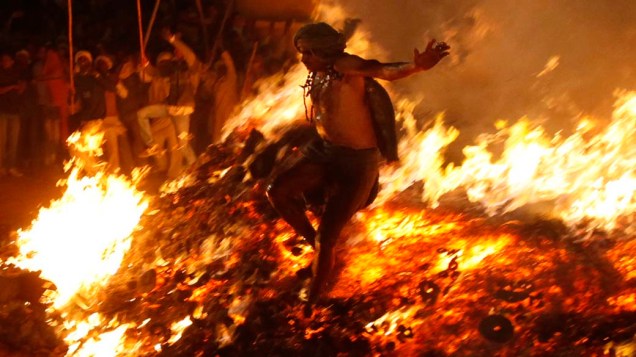 Sacerdote hindu salta por fogueira significando a queima de demônios durante ritual em Phalen, Índia
