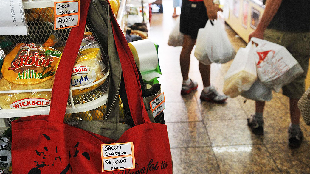 Sacolas ecológicas reutilizáveis, fabricadas com material que agride menos o meio ambiente, são vendidas no comércio para substituir as sacolas plásticas distribuídas gratuitamente aos clientes