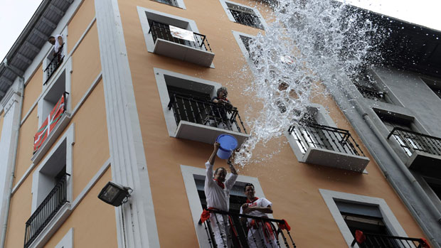 Foliões jogam àgua das sacadas durante o festival de São Firmino, em Pamplona