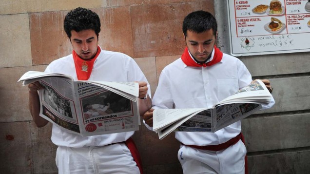 Foliões lêem jornal antes de corrida de touros, na Espanha