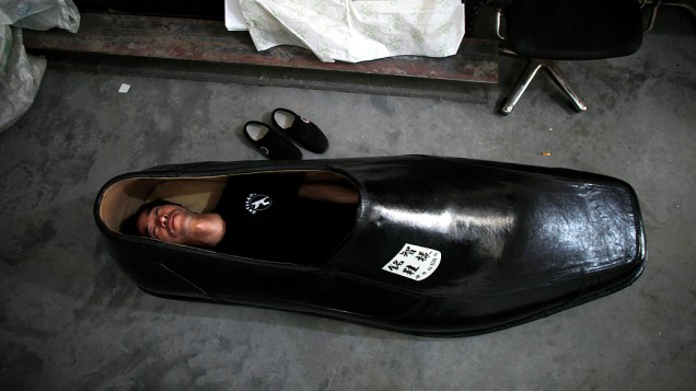 Designer de calçados se deita em uma de suas criações, um sapato gigante de 1,9 metros, em Wenling, na China