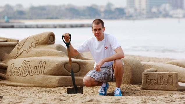 Sebastian Vettel posa ao lado de uma escultura de areia no formato de carro de F1 em Melbourne, na Austrália, em 26/03/2009<br>