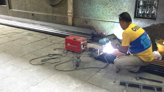 Funcionário prepara barras de ferro fixadas no portão lateral da Câmara de Vereadores do Rio